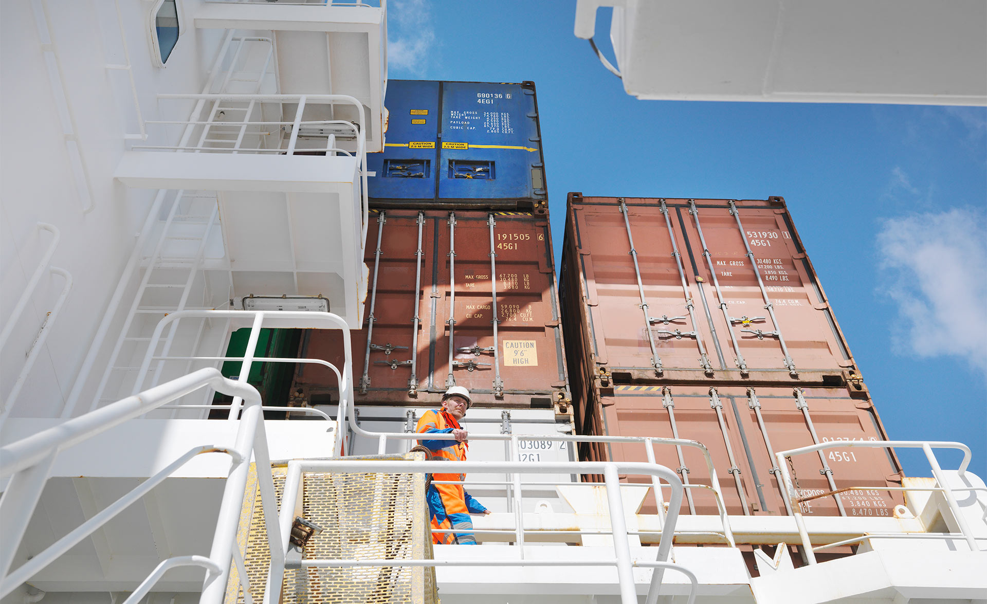 A person walks around on a cargo ship fully loaded with containers