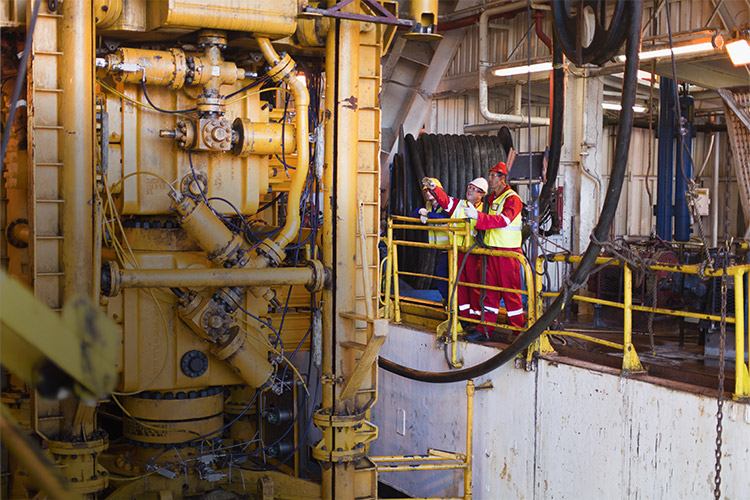 Technicians on an oil rig out at sea, perform service work