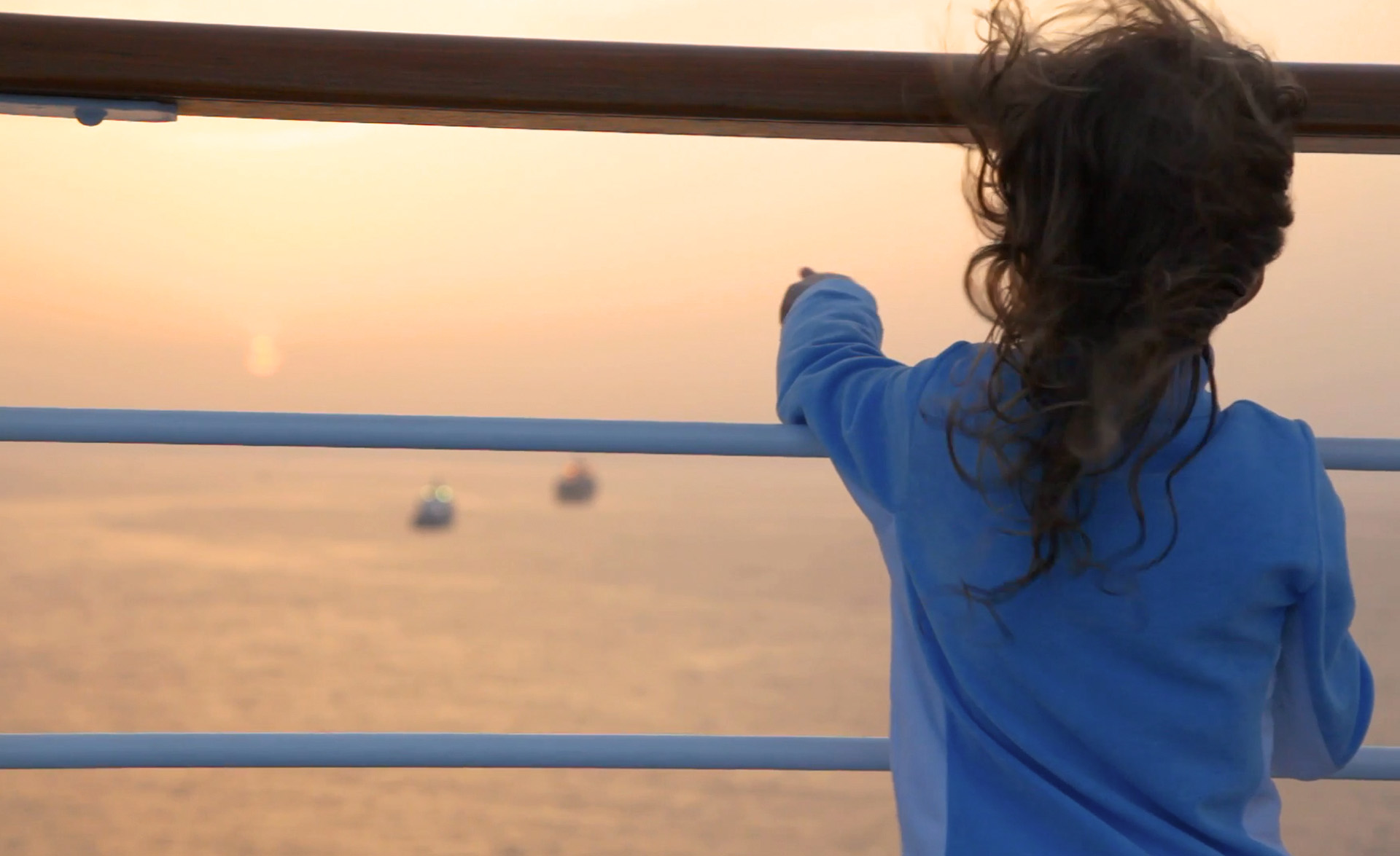 Girl looks out over the sea from a big ship